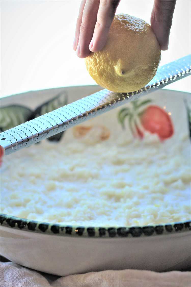 Zesting lemon over bowl with rice mixture for pastiera recipe.