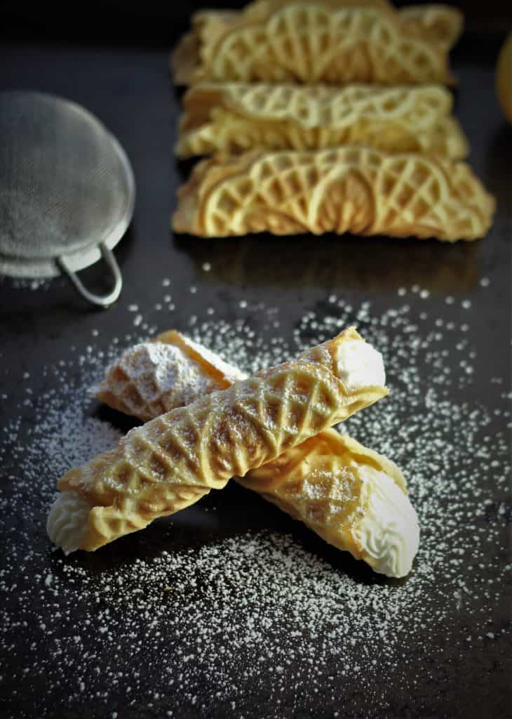 two ricotta filled pizzelle with pizzelle shells in background