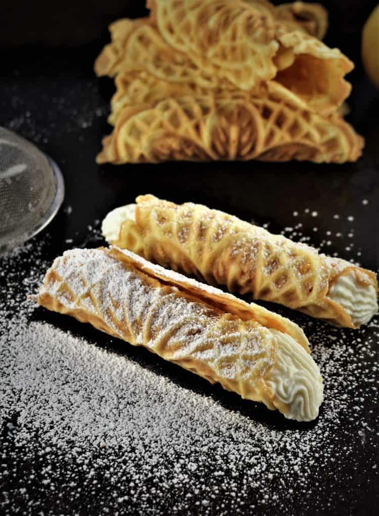 two pizzelle filled with ricotta and dusted with powdered sugar