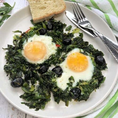 Fried eggs with greens plated with sliced bread.