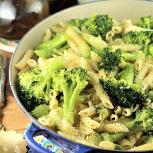 Broccoli pasta in large blue skillet topped with Parmigiano cheese.