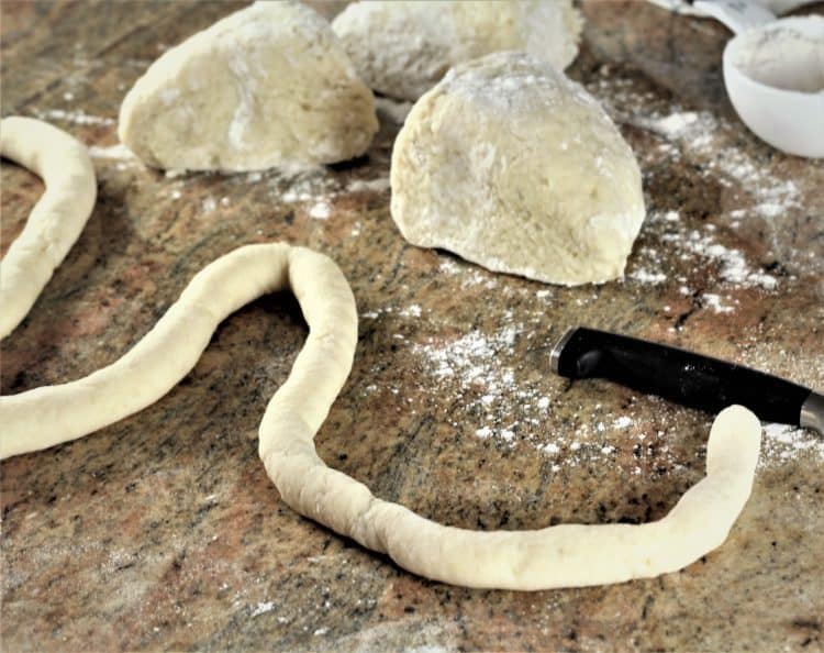 ropes of gnocchi dough with pieces of dough in the background