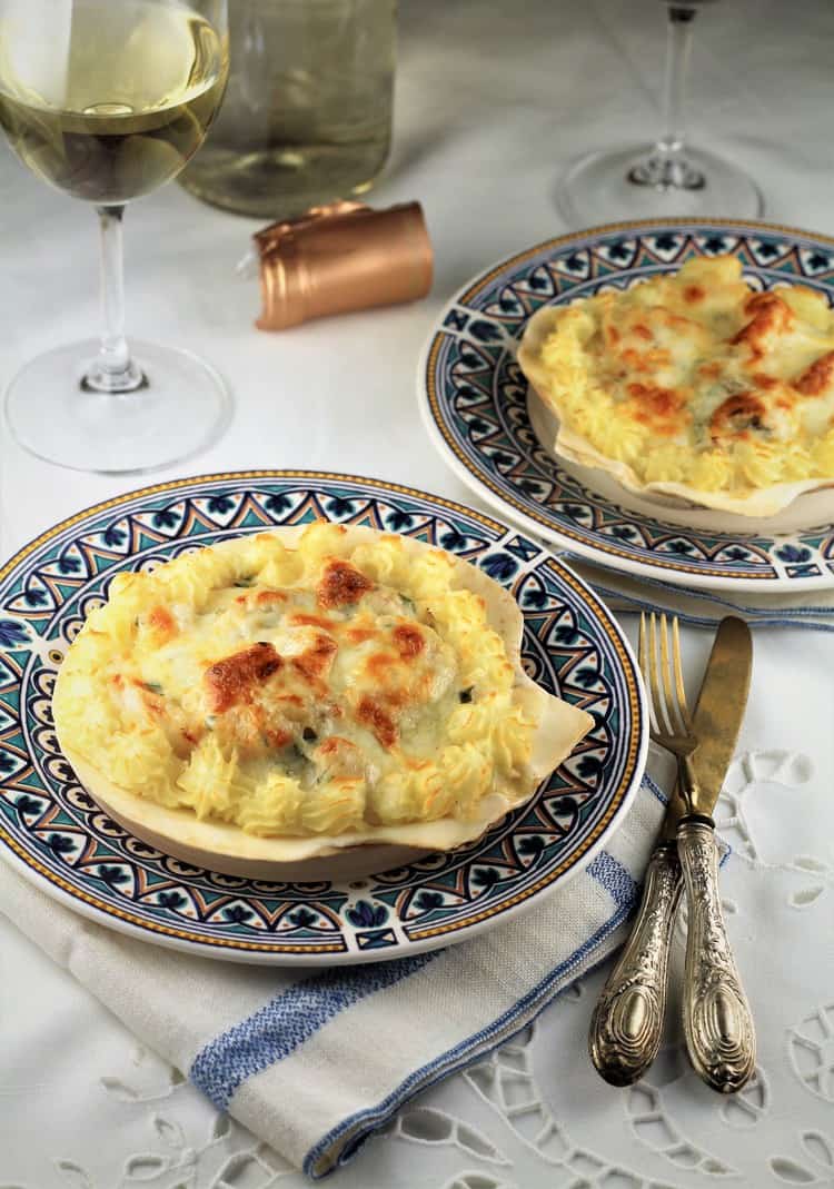 two blue dishes with seafood in scallop shell dishes with wine glasses and utensils