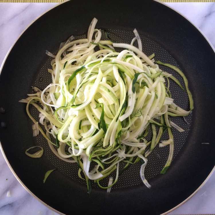 spiralized zucchini being sautéed in a pan
