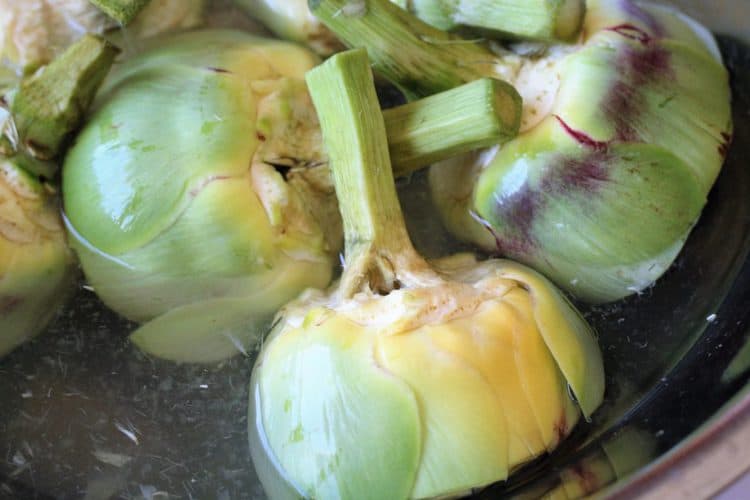 trimmed artichokes in a water and lemon juice bath