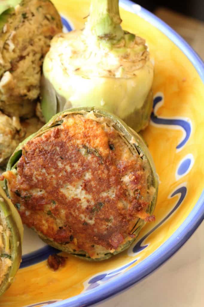 browned stuffed artichokes in a large yellow and blue bowl