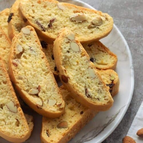 Classic almond biscotti piled on white round plate.