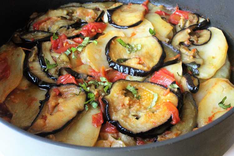 pan with sliced baked eggplant, potatoes, and tomato sauce