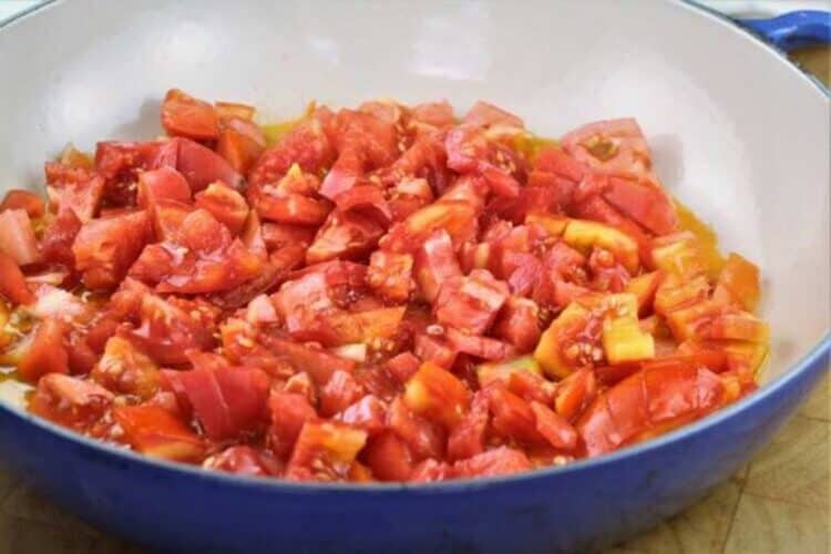 Chopped tomatoes in skillet simmering.