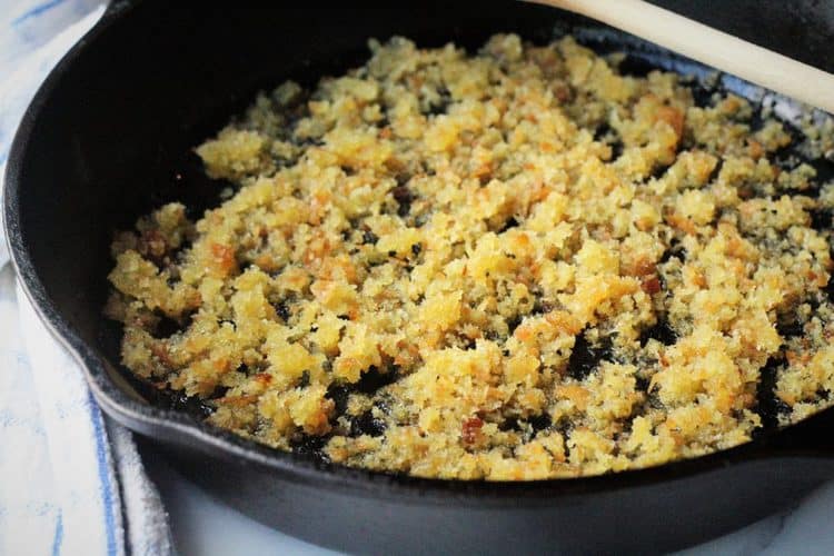 breadcrumbs being tossed with olive oil in a cast iron pan