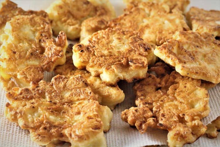 cauliflower fritters on a white plate covered in paper towels to absorb excess oil