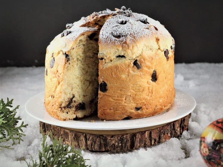  Almond and chocolate Panettone resting on wood board with one wedge sliced 