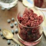 glass filled with blueberry granita wih fresh blueberries and spoon on side