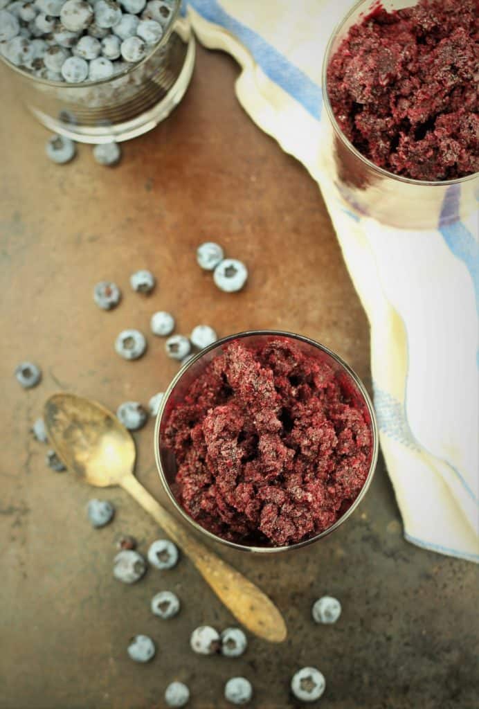 overhead view of 2 glasses with blueberry granita and glass filled with fresh blueberries