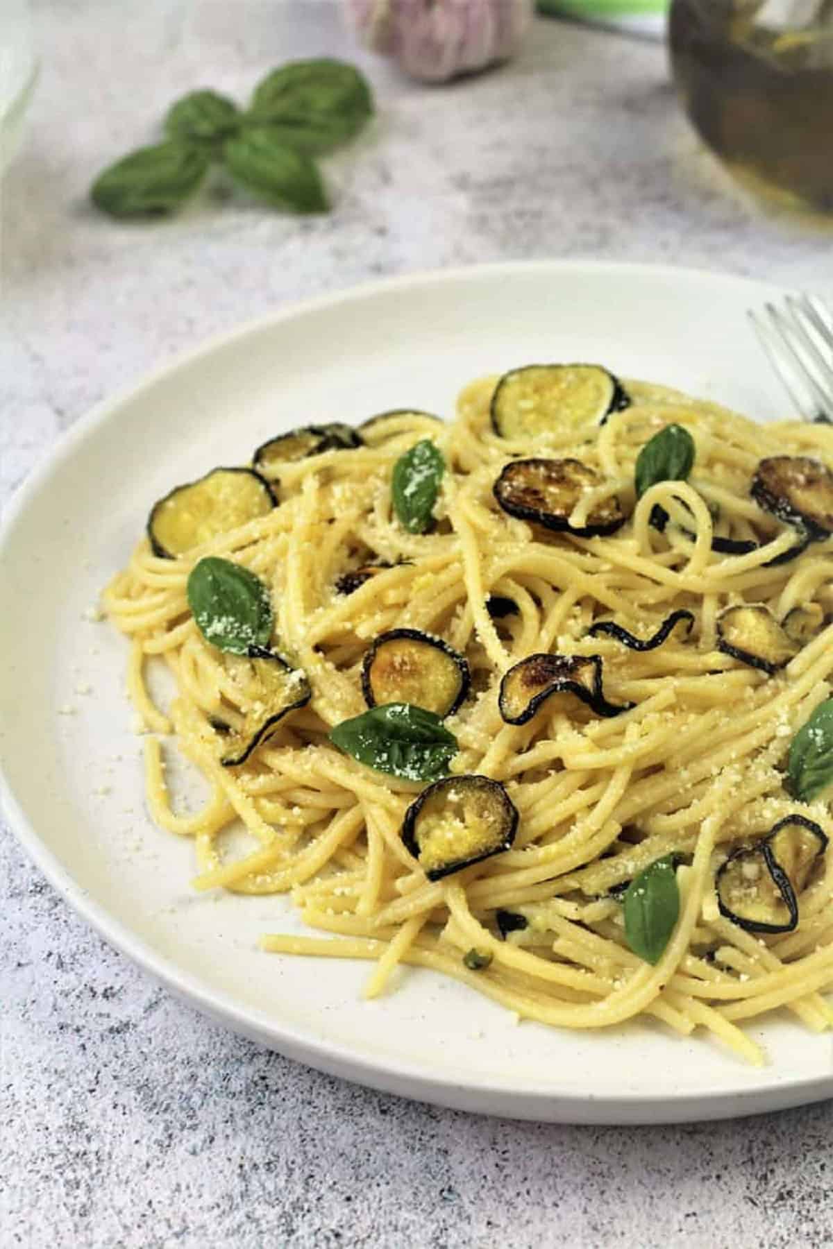 Spaghetti with Zucchini Pasta with zucchini topped with grated Parmigiano cheese on round plate.
