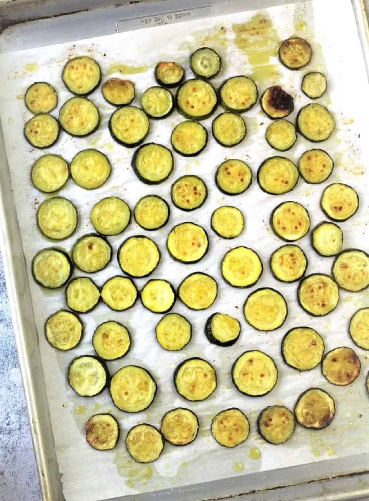 Golden, oven roasted zucchini rounds on baking sheet for pasta.