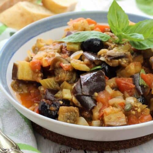 Sicilian eggplant caponata topped with fresh basil in bowl.