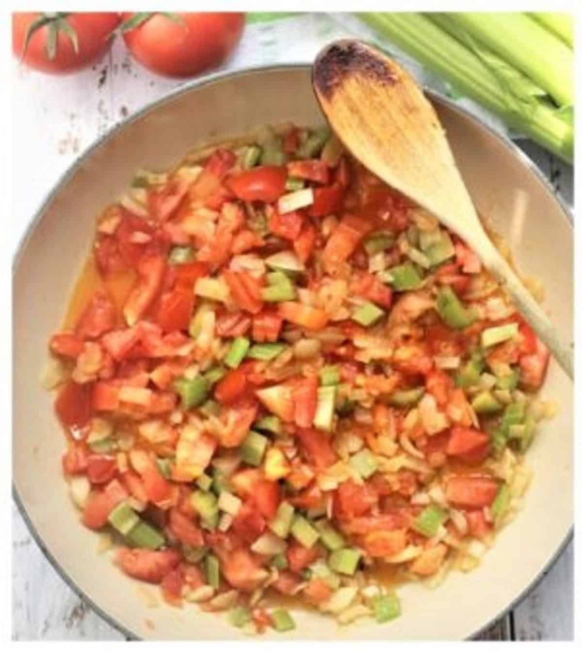 Sautéed tomatoes with onion and celery in skillet for caponata.