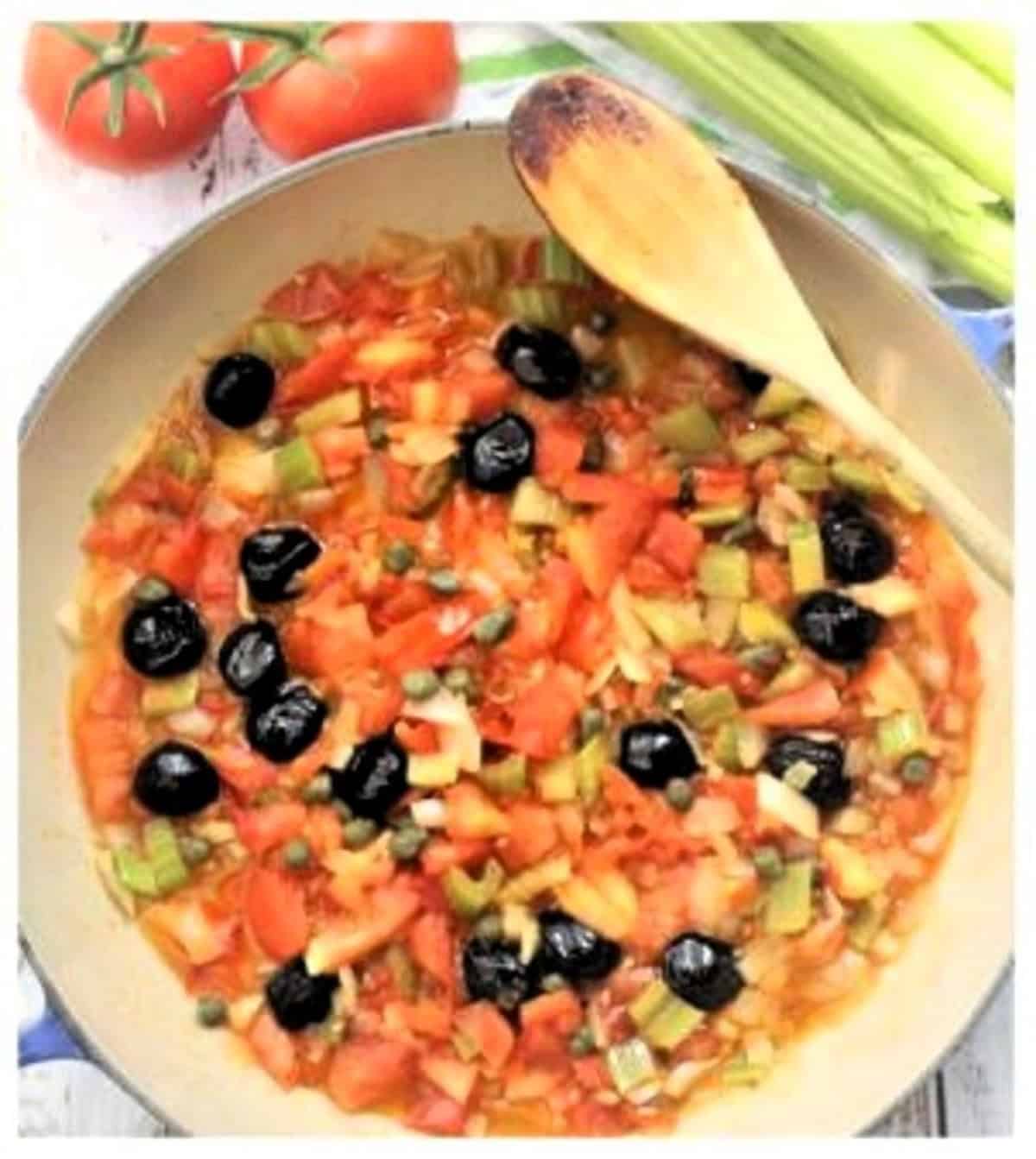 Olives and capers stirred into tomato mixture in skillet for caponata.