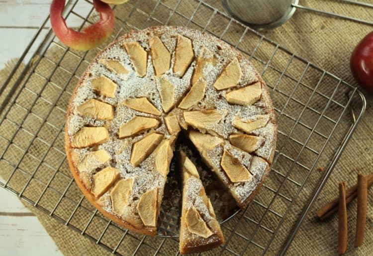 apple cake on wire rack with wedge cut from it