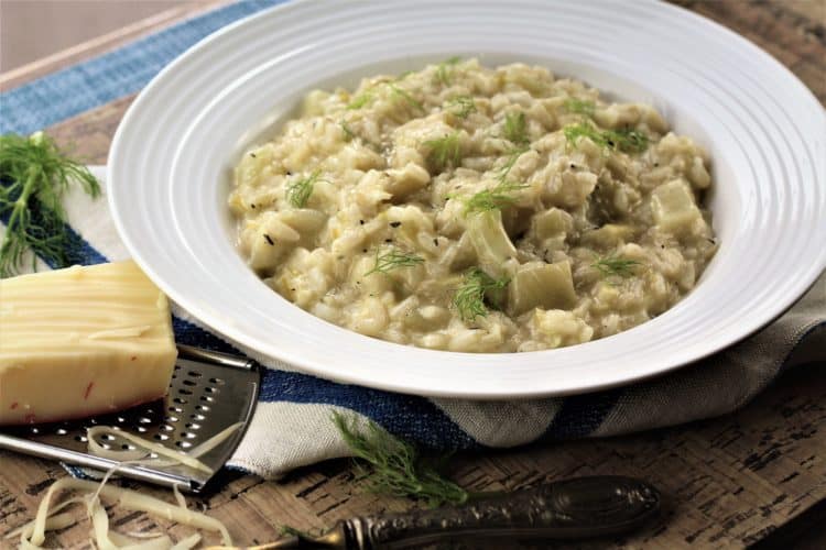 bowl of risotto with fennel and leeks with a cheese grater and piece of cheese