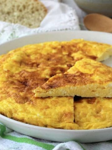 Frittata with ricotta on plate with wedge cut out.