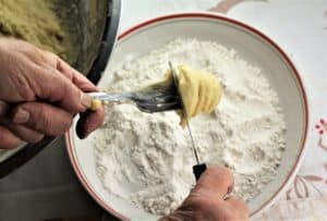 dough for sweet anise taralli being scraped into a bowl of flour