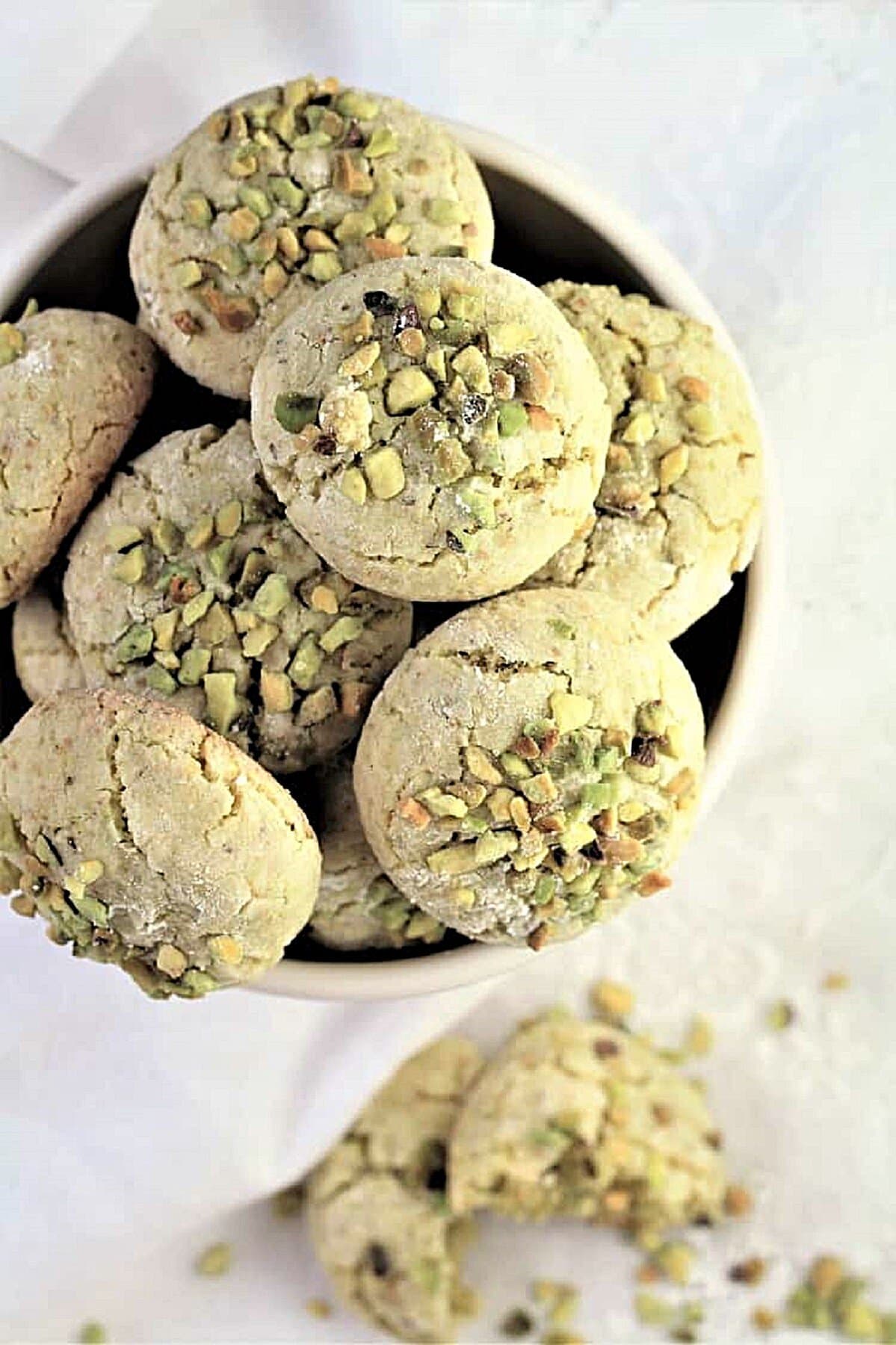 Pistachio Amaretti Pistachio amaretti in bowl with one cookie crumbled on the side.