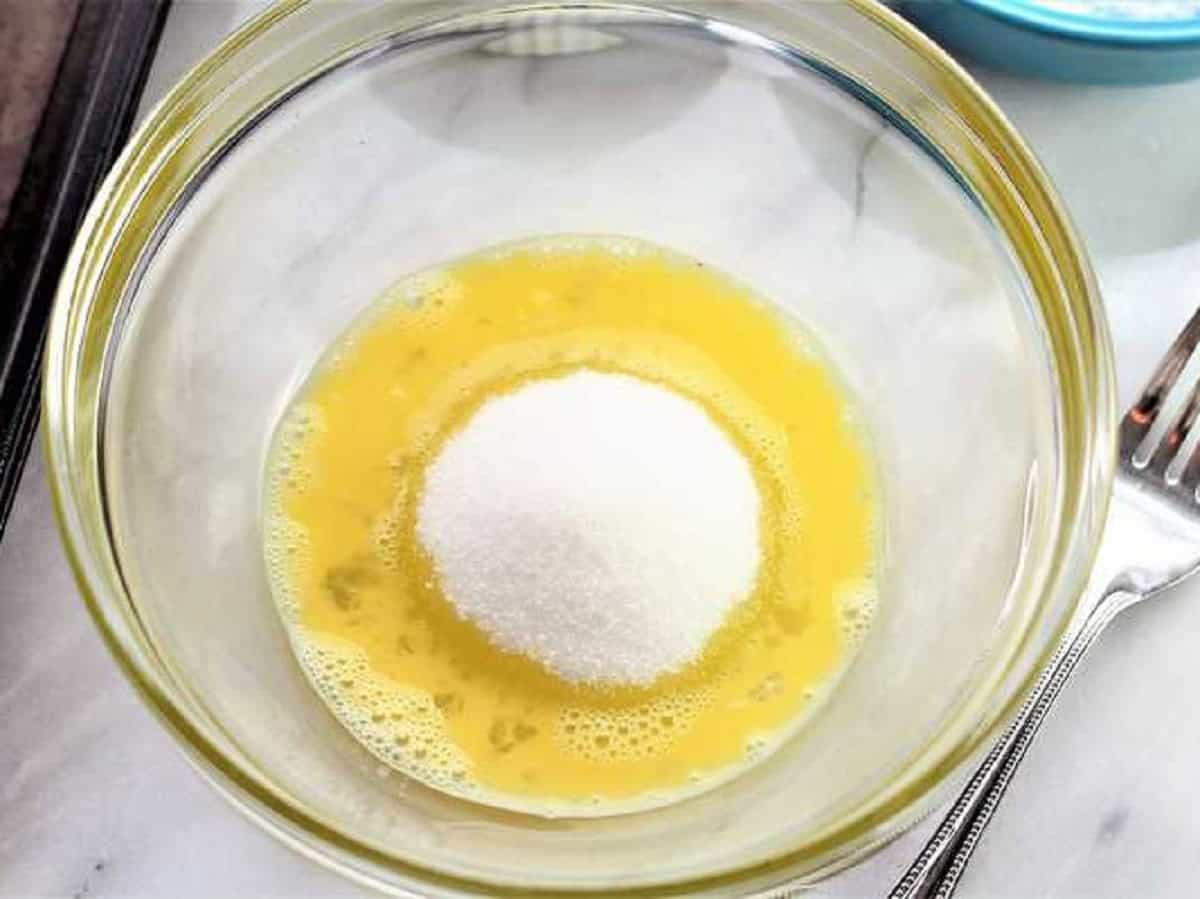 Egg and sugar in bowl for pistachio amaretti recipe.