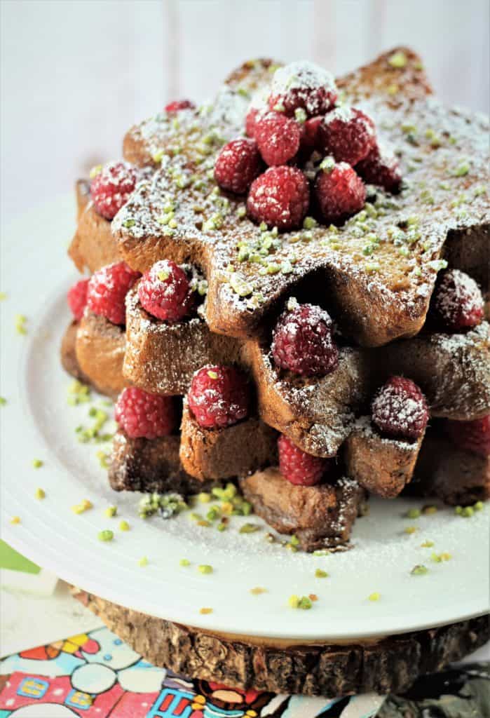 presentation of Pandoro french toast with raspberries, pistachios and powdered sugar