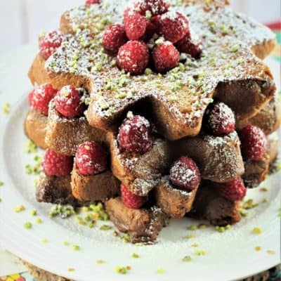 Pandoro french toast topped with powdered sugar, raspberries and pistachios