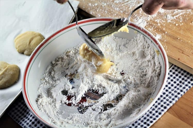 cookie dough being scooped into bowl with flour