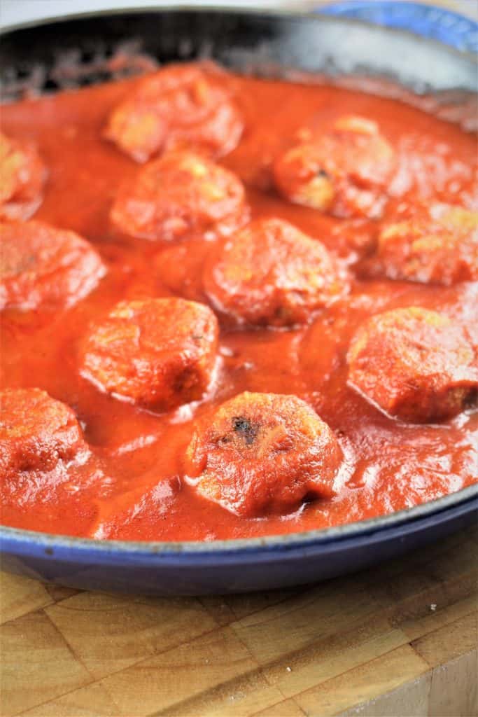 Baked eggplant meatballs simmering in tomato sauce.