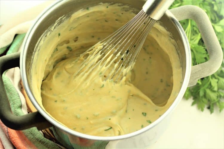 cooked panelle mixture in a sauce pan with whisk and parsley on side