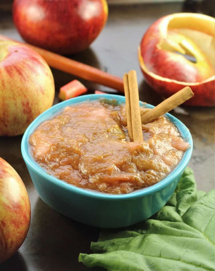 blue bowl filled with rhubarb applesauce surrounded by apples