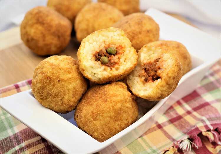 Sicilian arancini in a plate with one cut open to show interior 