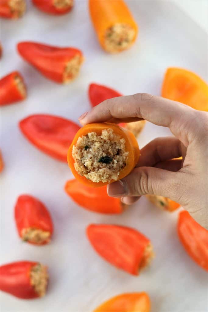 mini stuffed pepper held by hand with other peppers in background