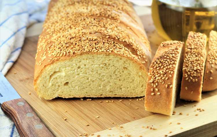 cross view of semolina bread with 3 slices cut and olive oil bottle in background