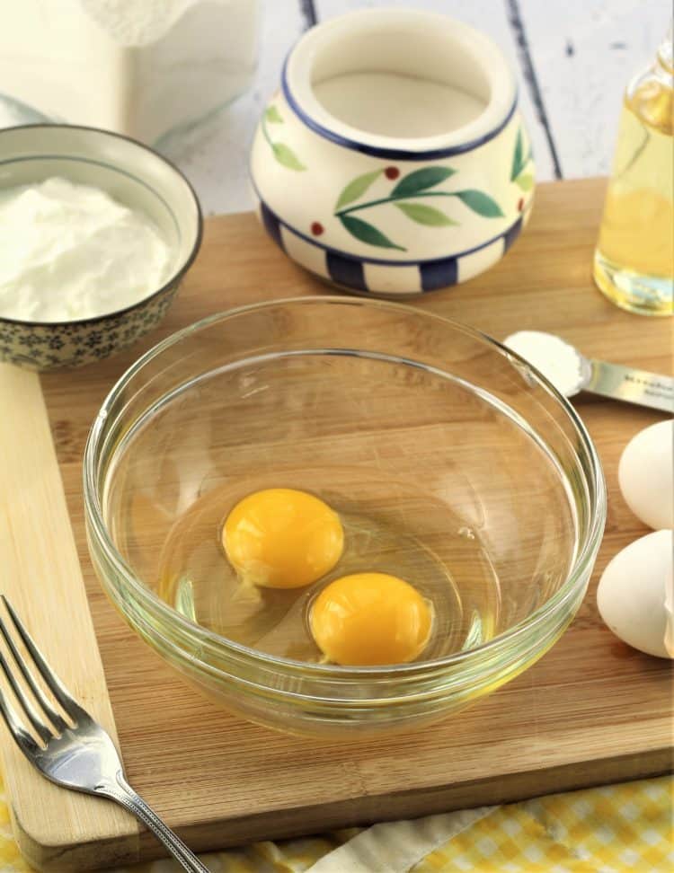 glass bowl with eggs, yogurt, flour and sugar in background