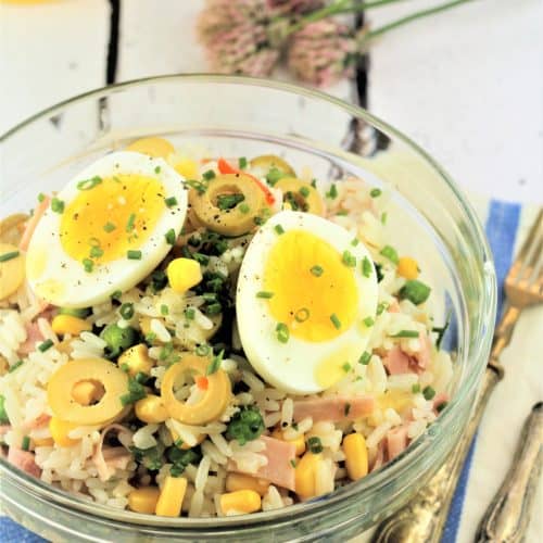 glass bowl filled with rice salad topped with halved hard boiled egg