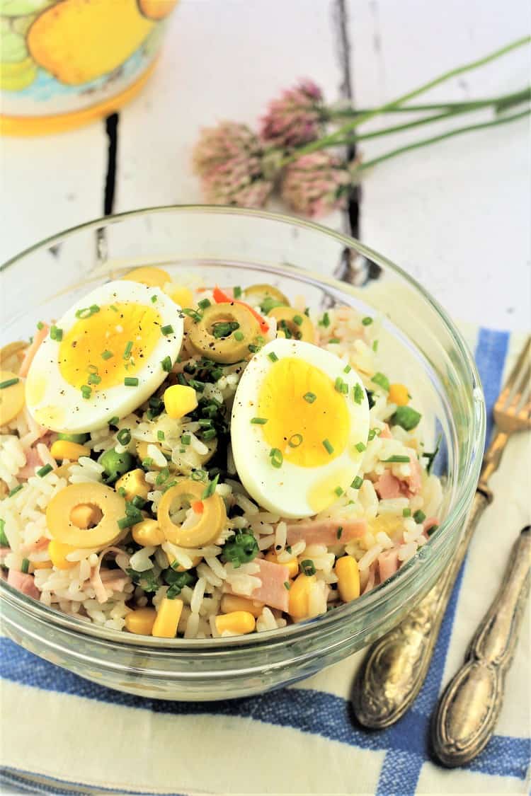 rice salad topped with hard boiled eggs in a glass bowl with fork on the side