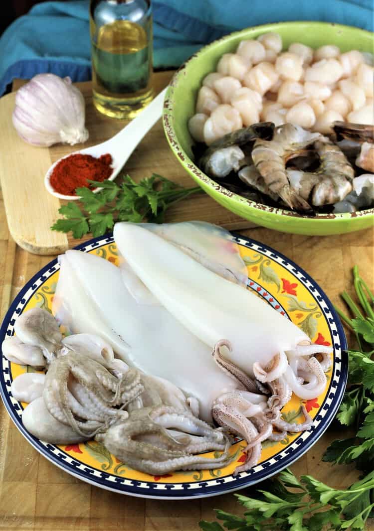 bowl with scallops and shrimp in background and plate with squid tubes and baby octopus