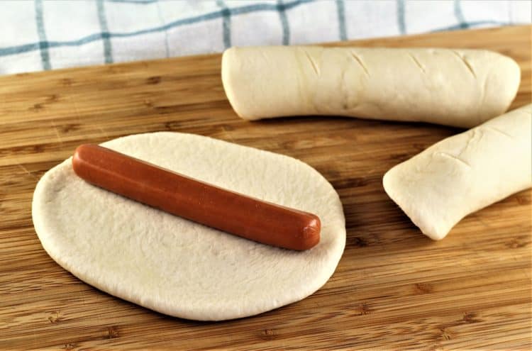 placing hot dog on dough to make rollo con wurstel