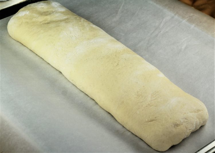 elongated shape of semolina bread dough on baking sheet