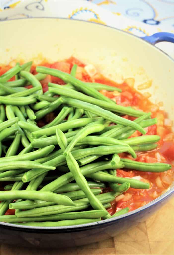pan with diced tomatoes topped with fresh green beans
