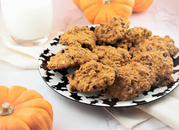 plate filled with cookies and glass of milk and mini pumpkins in background