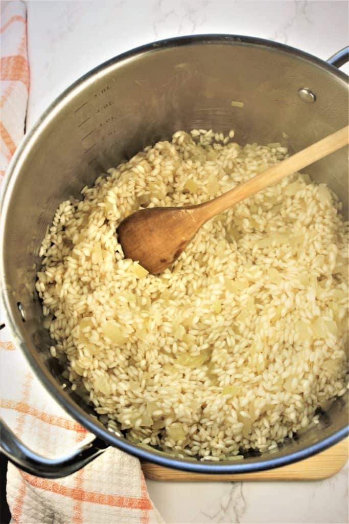 risotto being stirred with wooden spoon in saucepan