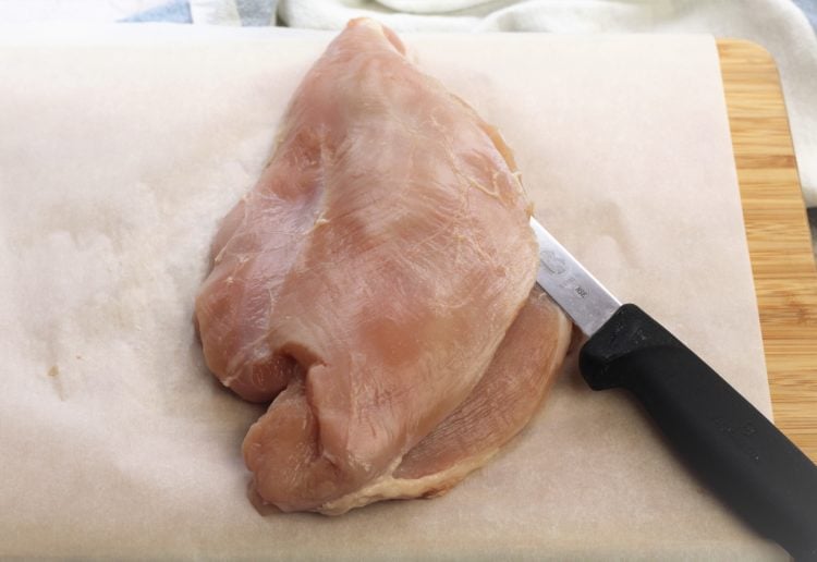 whole turkey breast on parchment paper with knife cut into it
