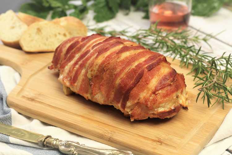whole Bacon Covered Turkey Roulade with Mushroom Filling on wood board