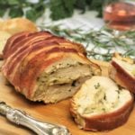 sliced Bacon Covered Turkey Roulade with Mushroom Filling on wood board
